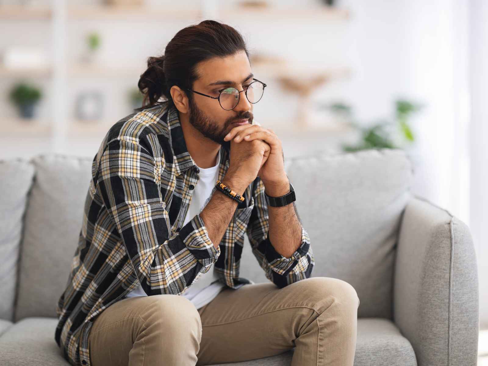 A man sitting on a sofa looking stressed and worried, illustrating the experience of anticipatory flight anxiety at home